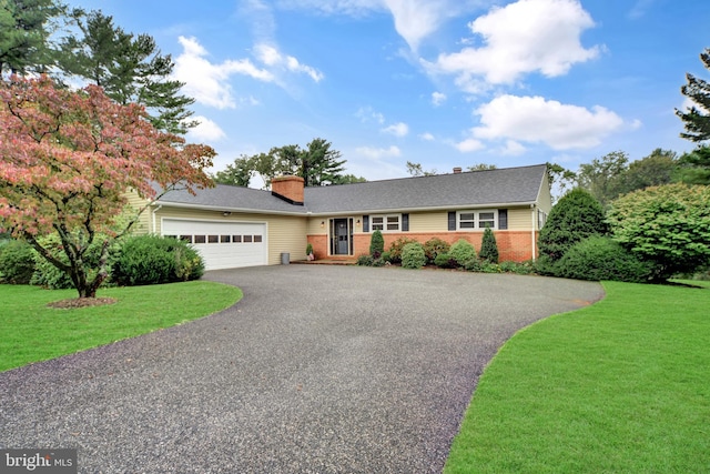 single story home with driveway, an attached garage, brick siding, a front yard, and a chimney