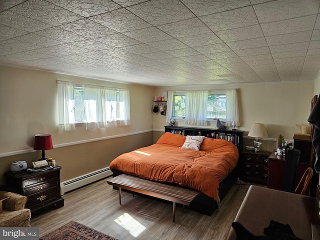 bedroom featuring a baseboard heating unit and wood finished floors