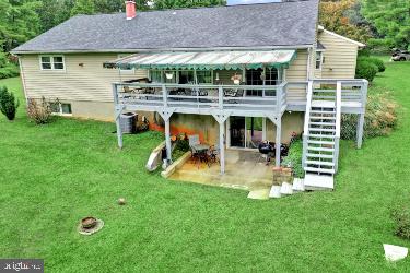 rear view of house with a deck, a lawn, and a patio