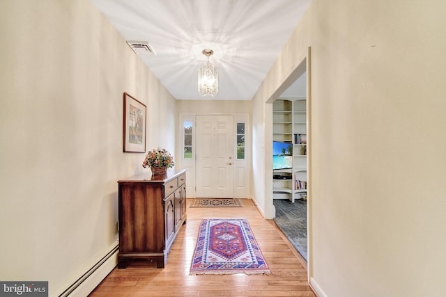 foyer entrance featuring a chandelier, a baseboard radiator, light wood-type flooring, and baseboards
