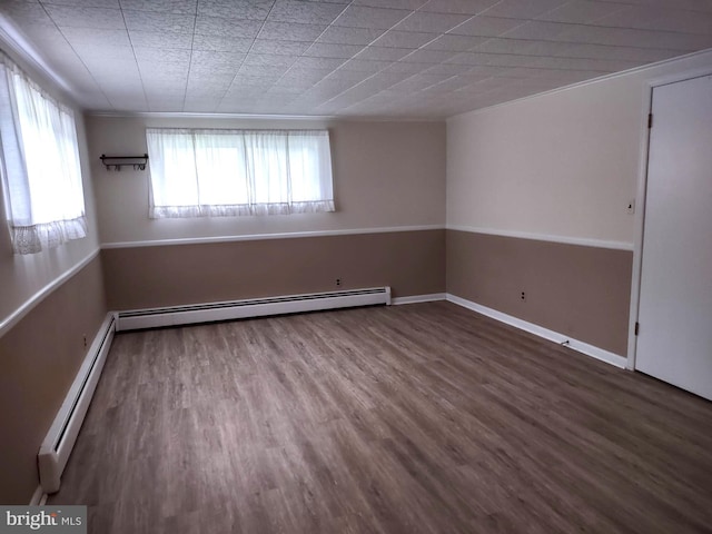 spare room with plenty of natural light, a baseboard heating unit, and wood finished floors