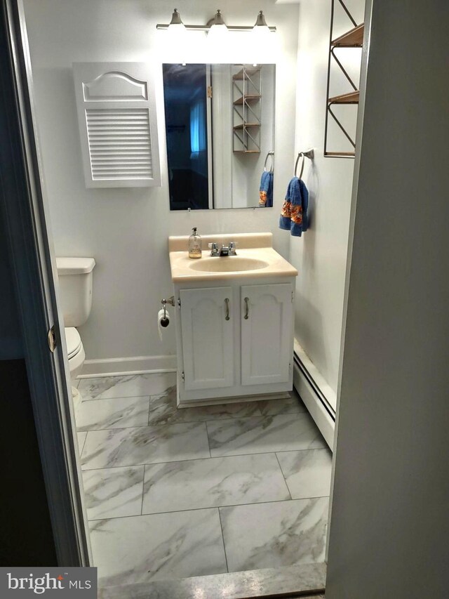 half bath with baseboard heating, marble finish floors, toilet, vanity, and baseboards