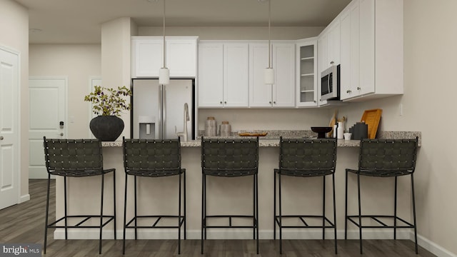 kitchen with white fridge with ice dispenser, a kitchen bar, white cabinetry, and dark wood-type flooring