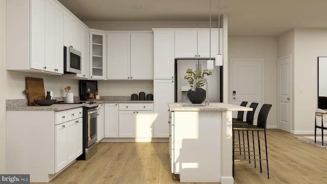 kitchen with a kitchen island, stainless steel appliances, light wood-type flooring, and white cabinetry