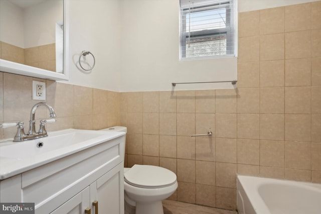 bathroom with tile walls, a bathtub, vanity, and toilet