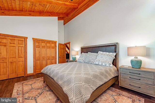 bedroom featuring vaulted ceiling with beams, multiple closets, wooden ceiling, and dark wood-type flooring