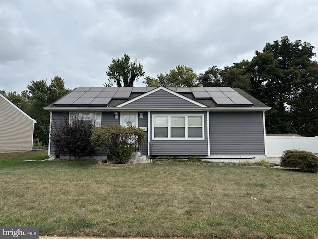 view of front of property featuring solar panels and a front lawn