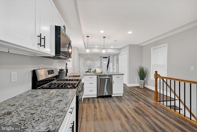 kitchen featuring light stone counters, white cabinets, pendant lighting, appliances with stainless steel finishes, and dark hardwood / wood-style flooring