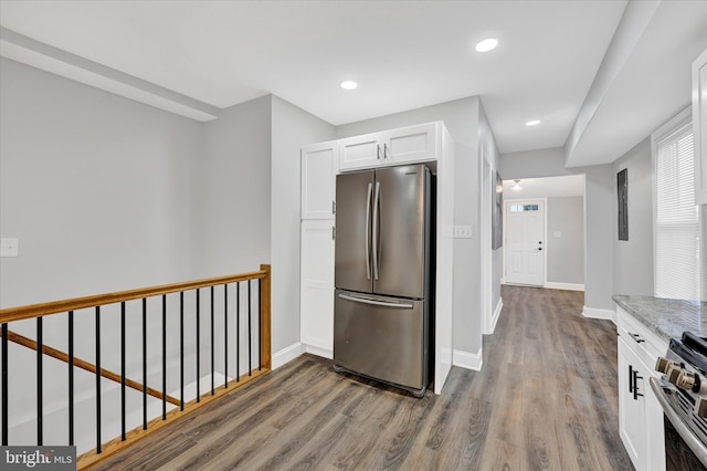 kitchen featuring light stone counters, white cabinets, stainless steel appliances, and dark wood-type flooring