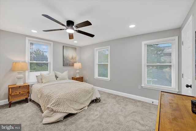 carpeted bedroom featuring multiple windows and ceiling fan