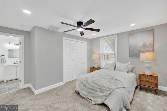 carpeted bedroom with sink, ceiling fan, ensuite bathroom, and a closet