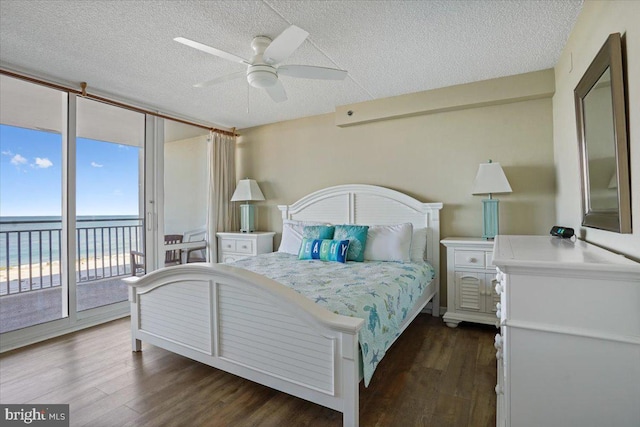 bedroom featuring access to outside, dark wood-type flooring, a water view, and ceiling fan