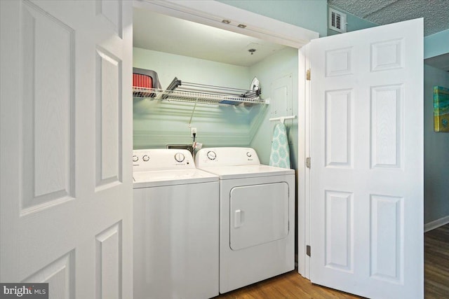 laundry room with separate washer and dryer, a textured ceiling, and light wood-type flooring