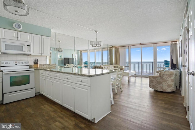 kitchen featuring dark hardwood / wood-style floors, kitchen peninsula, white appliances, and white cabinetry