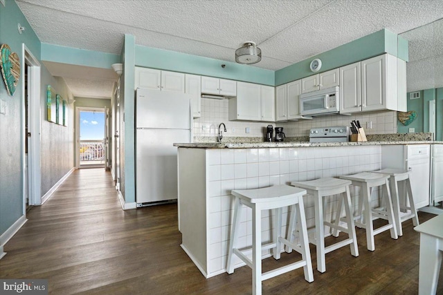 kitchen featuring white appliances, white cabinetry, and dark hardwood / wood-style flooring