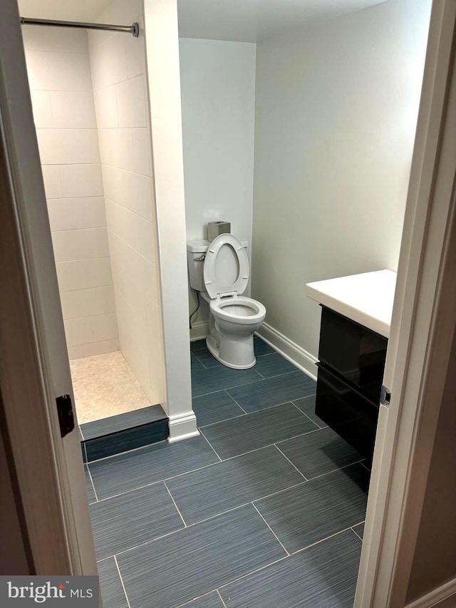 bathroom featuring vanity, toilet, and tiled shower