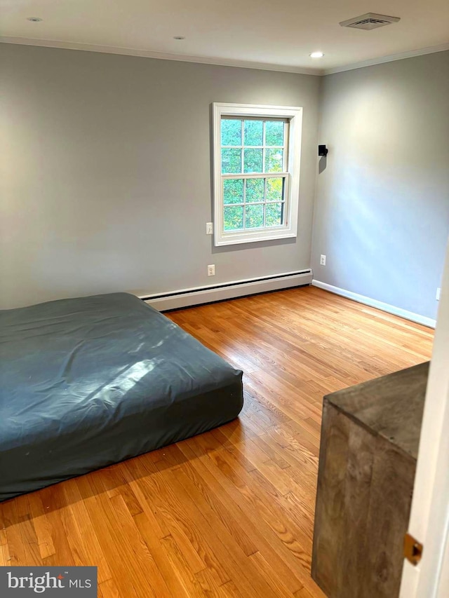 unfurnished bedroom with a baseboard radiator, ornamental molding, and light hardwood / wood-style floors