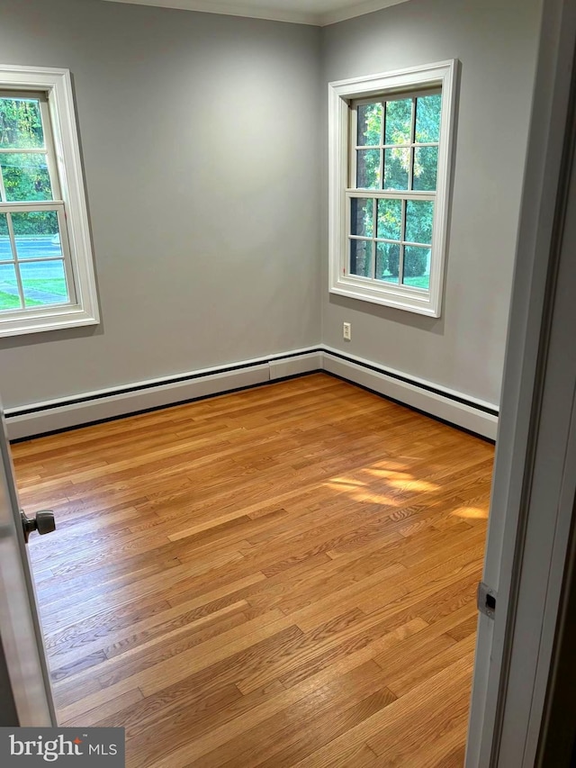 unfurnished room with baseboard heating, a healthy amount of sunlight, and light hardwood / wood-style flooring