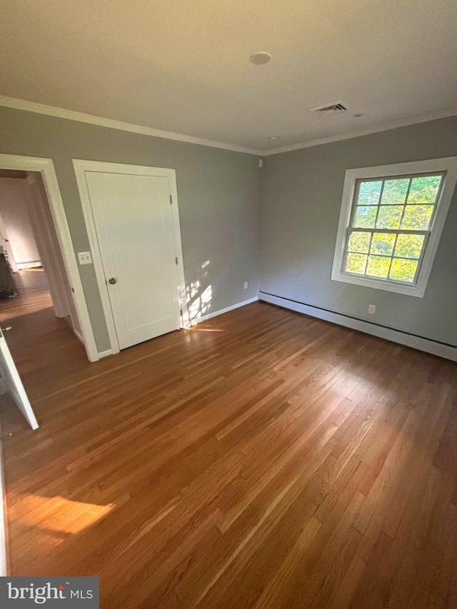 interior space featuring a baseboard heating unit, crown molding, and wood-type flooring