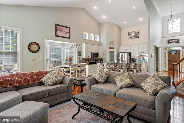 living room featuring an inviting chandelier, light hardwood / wood-style floors, and high vaulted ceiling