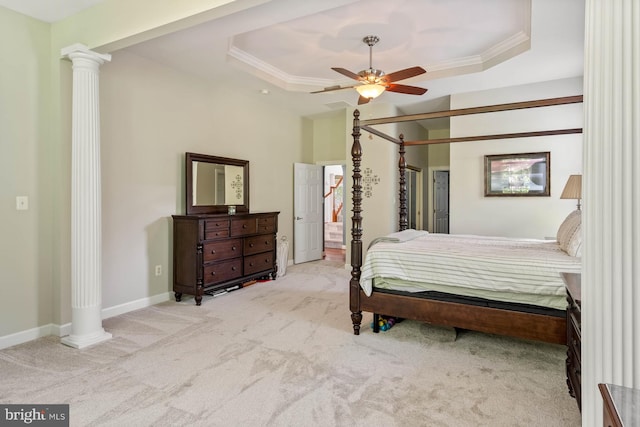 carpeted bedroom with a raised ceiling, ornamental molding, ceiling fan, and ornate columns