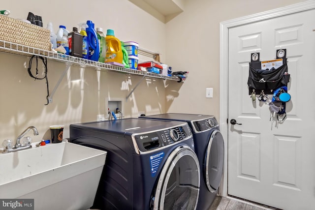 laundry room with wood-type flooring, separate washer and dryer, and sink