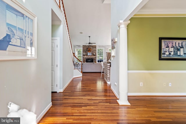 hall featuring ornate columns, dark hardwood / wood-style floors, and crown molding