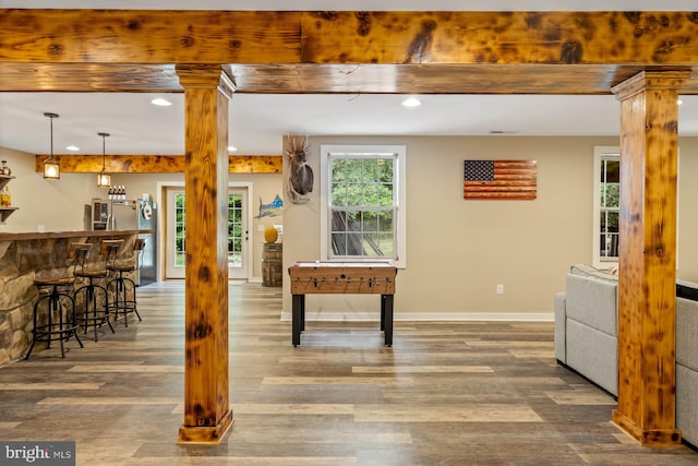 interior space with hardwood / wood-style flooring, bar, and ornate columns