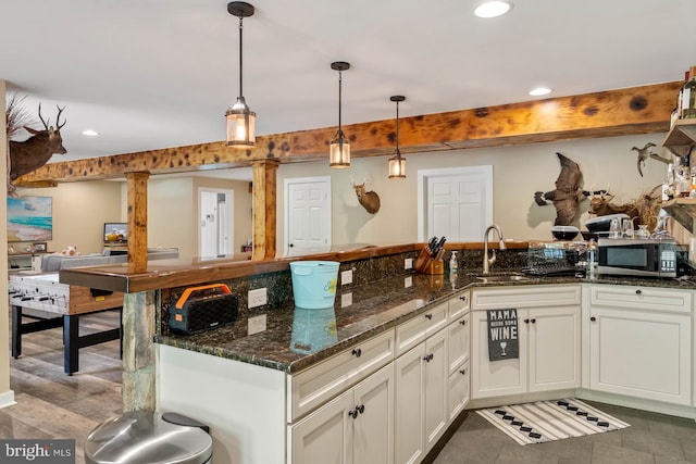 kitchen with dark stone countertops, decorative light fixtures, and sink