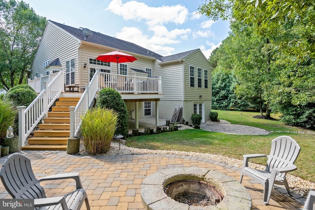 rear view of property featuring a fire pit, a deck, a yard, and a patio area