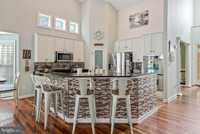 kitchen featuring white cabinetry, a towering ceiling, and stainless steel appliances