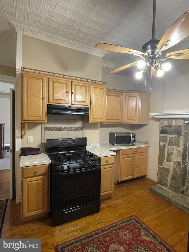 kitchen with backsplash, black range with gas cooktop, ceiling fan, and hardwood / wood-style flooring