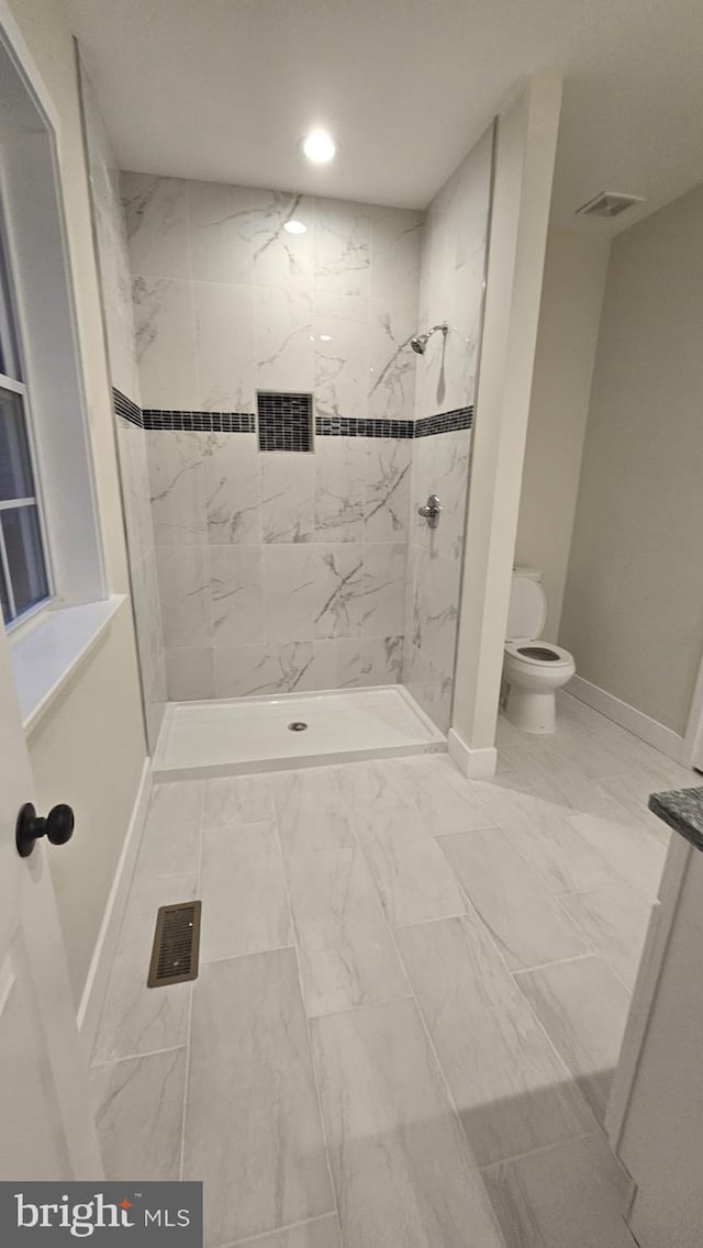 bathroom featuring a tile shower and toilet