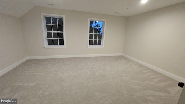 carpeted empty room with lofted ceiling