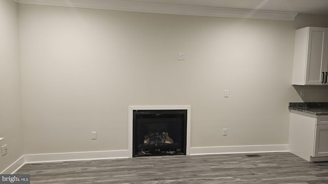 unfurnished living room featuring crown molding and dark hardwood / wood-style flooring