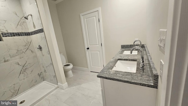 bathroom with a tile shower, vanity, and toilet