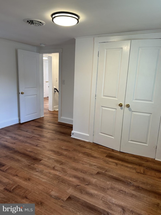 unfurnished bedroom with dark hardwood / wood-style flooring and a closet