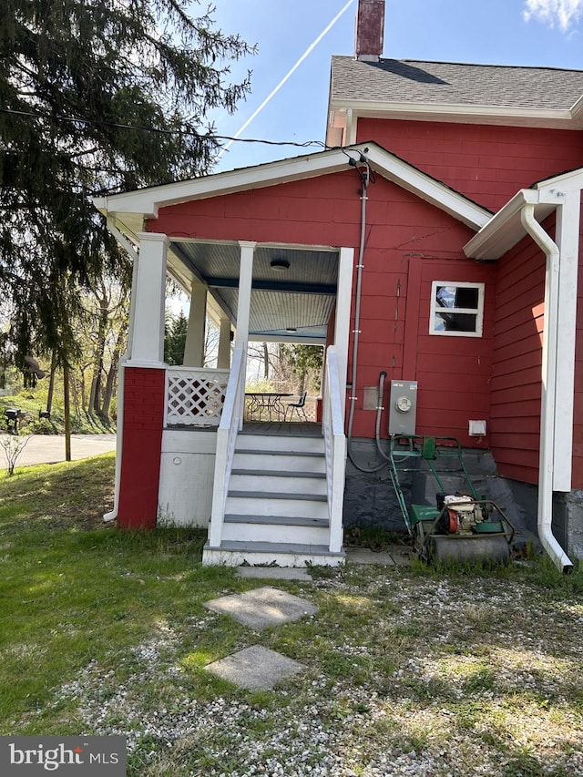 rear view of property featuring a lawn and a porch