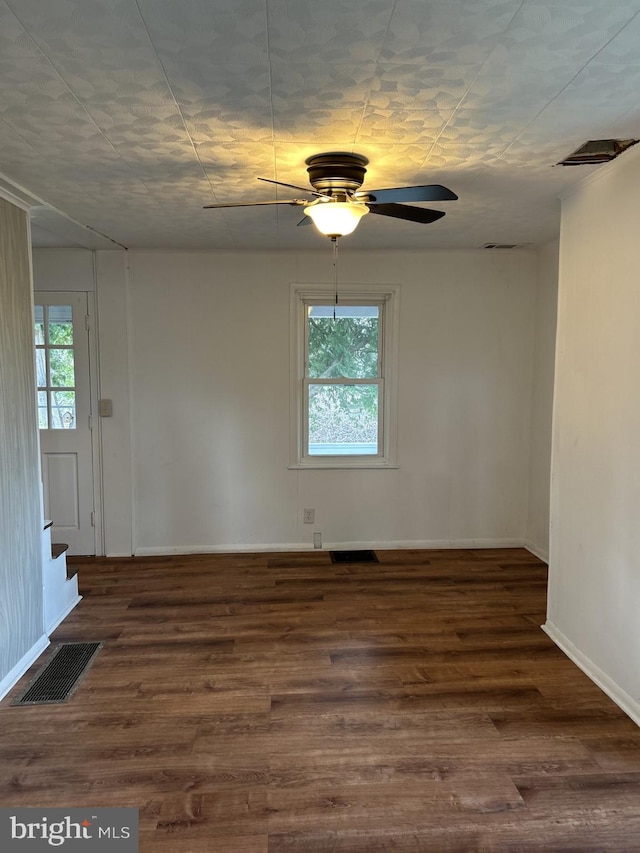 spare room with a wealth of natural light, ceiling fan, and dark wood-type flooring