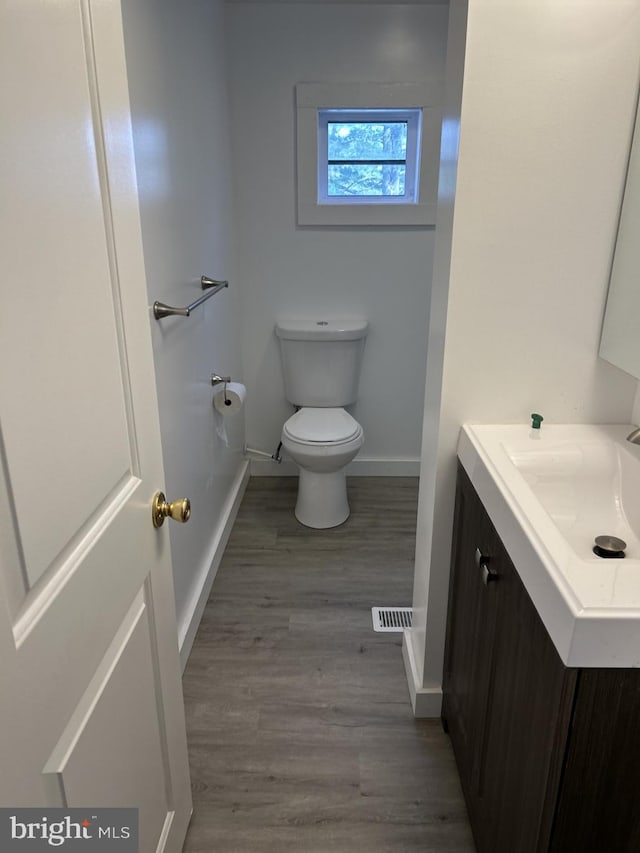 bathroom featuring wood-type flooring, vanity, and toilet