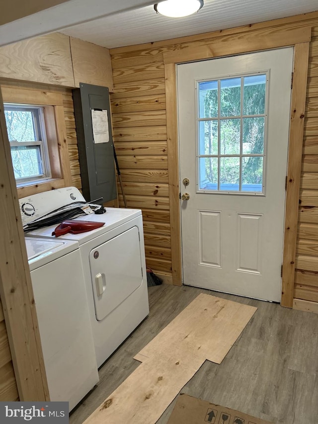 laundry room featuring washing machine and clothes dryer, a wealth of natural light, hardwood / wood-style flooring, and electric panel