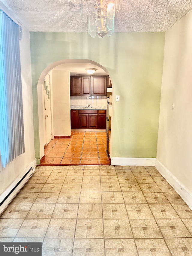 interior space with an inviting chandelier, a textured ceiling, sink, and a baseboard radiator