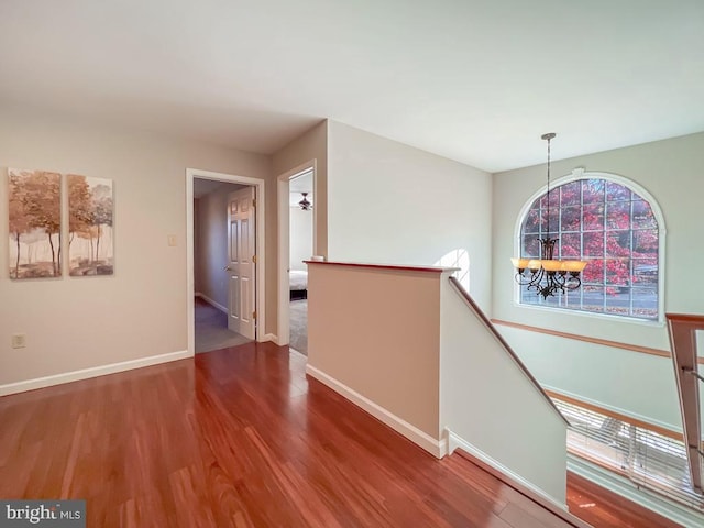 corridor featuring wood-type flooring and a notable chandelier