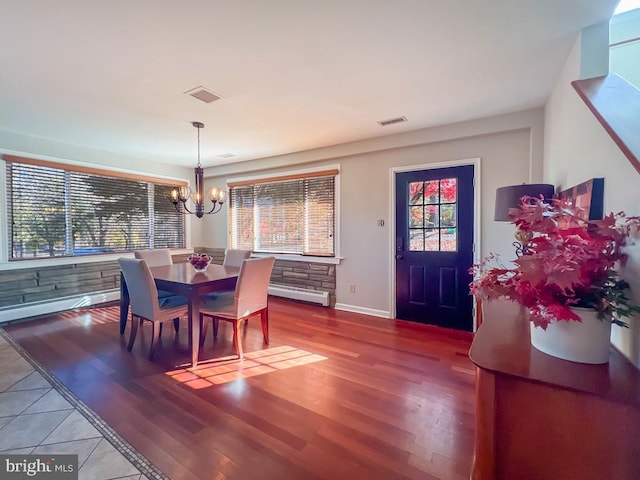 dining space with hardwood / wood-style floors and an inviting chandelier