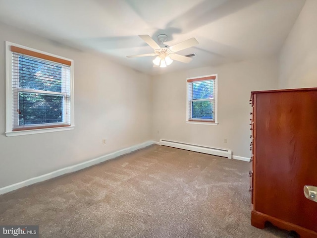 empty room featuring ceiling fan, a wealth of natural light, baseboard heating, and carpet floors