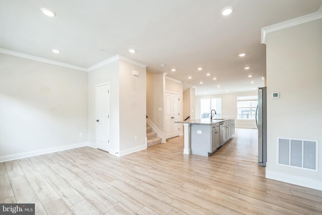 kitchen featuring stainless steel refrigerator, a center island with sink, light wood-type flooring, and sink