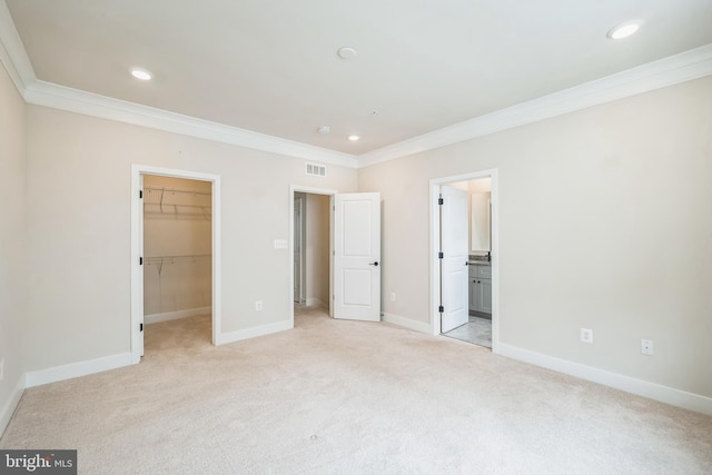 unfurnished bedroom with a spacious closet, connected bathroom, and crown molding