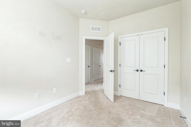 unfurnished bedroom featuring light colored carpet and a closet