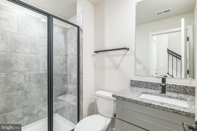 bathroom with vanity, a shower with shower door, and toilet