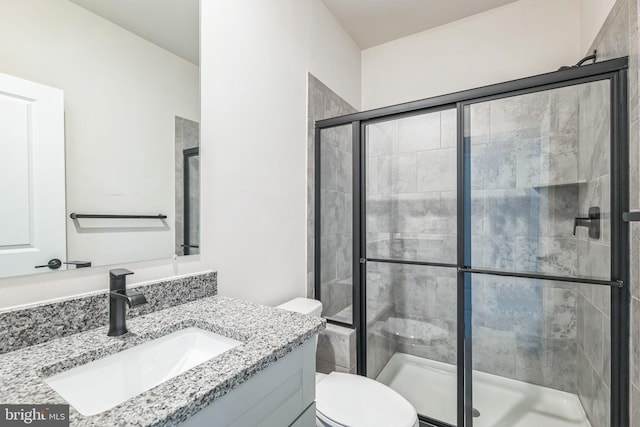 bathroom with vanity, toilet, and a shower with door